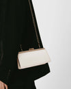 Sac JEANNE BAGUETTE Ivoire porté à l'épaule avec chaîne, détail du fermoir rétro, sur tailleur noir
