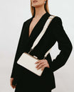 Sac JEANNE BAGUETTE Ivoire porté en bandoulière, fermoir rétro en gros plan sur blazer noir