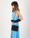 Sac JEANNE noir porté en bandoulière avec chaîne, vue de profil sur modèle en robe bleue
