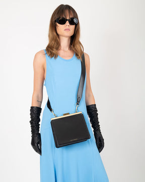 Sac JEANNE noir porté en bandoulière croisée, fermoir métallique, porté par une femme en robe bleue