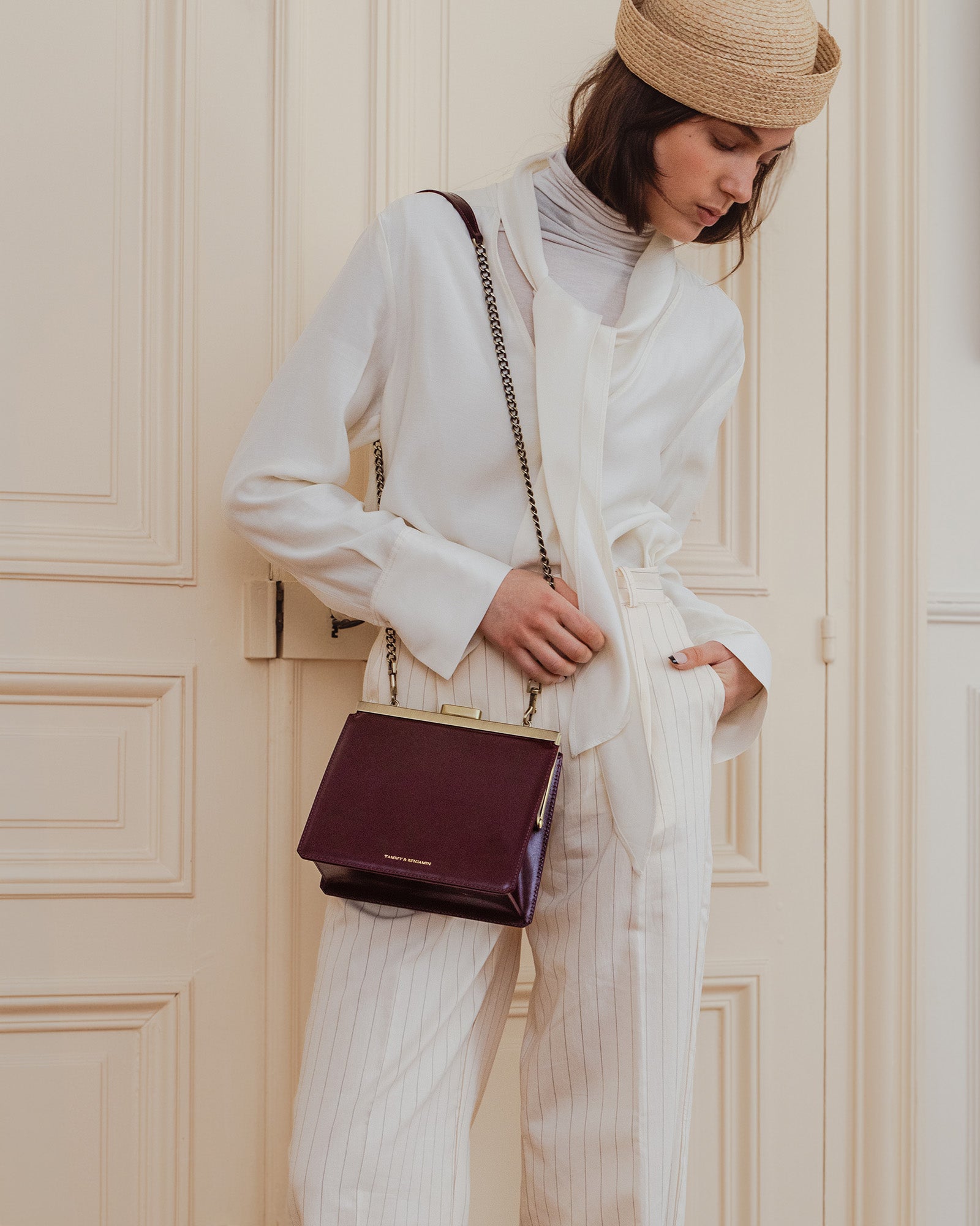 Sac JEANNE Mahogany porté en bandoulière avec chaîne, vue de face sur une femme