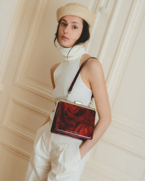 Sac JEANNE en cuir marbré rouge, porté en bandoulière, fermoir métallique doré visible de face