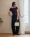 Sac JUDE ivoire matelassé porté à la main par une mannequin, tenue chemisier et pantalon large