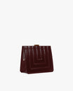 JUDE bag in quilted Mahogany, side view with folded handle against the body, gold clasp visible