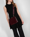 JUDE bag in Mahogany quilted leather worn crossbody, front view with black dress
