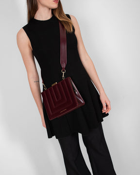 JUDE bag in Mahogany quilted leather worn crossbody, front view with black dress