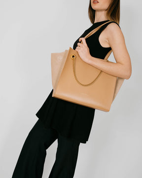 Sac LEXI MM Beige porté à l'épaule, vue de profil avec chaîne amovible et panneaux en suède