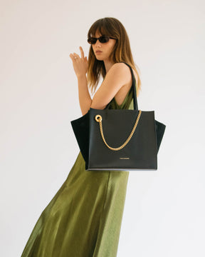 Sac LEXI MM noir porté à l'épaule, ailes en cuir et panneaux en suède, chaîne amovible