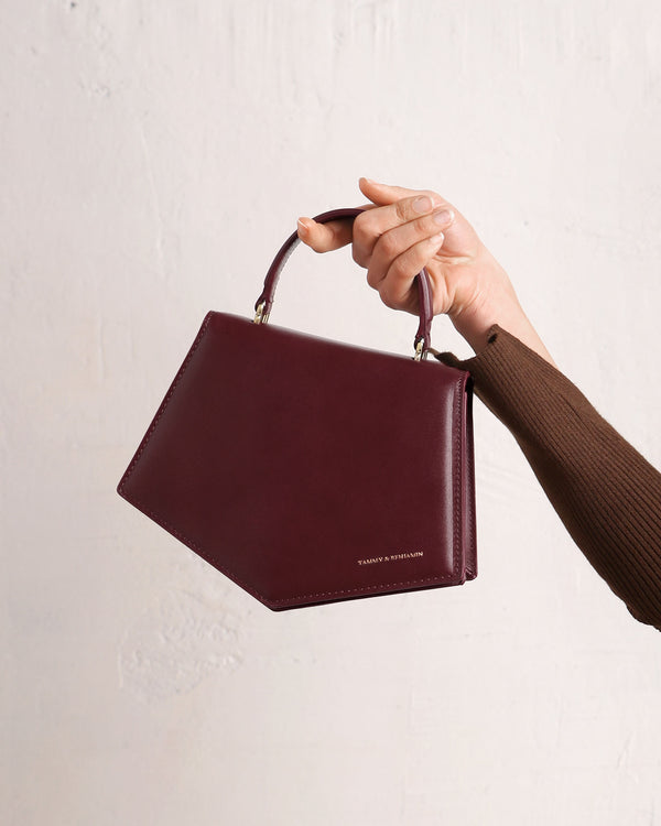 Sac PENTAGONE Mahogany tenu à la main par la poignée, vue de face