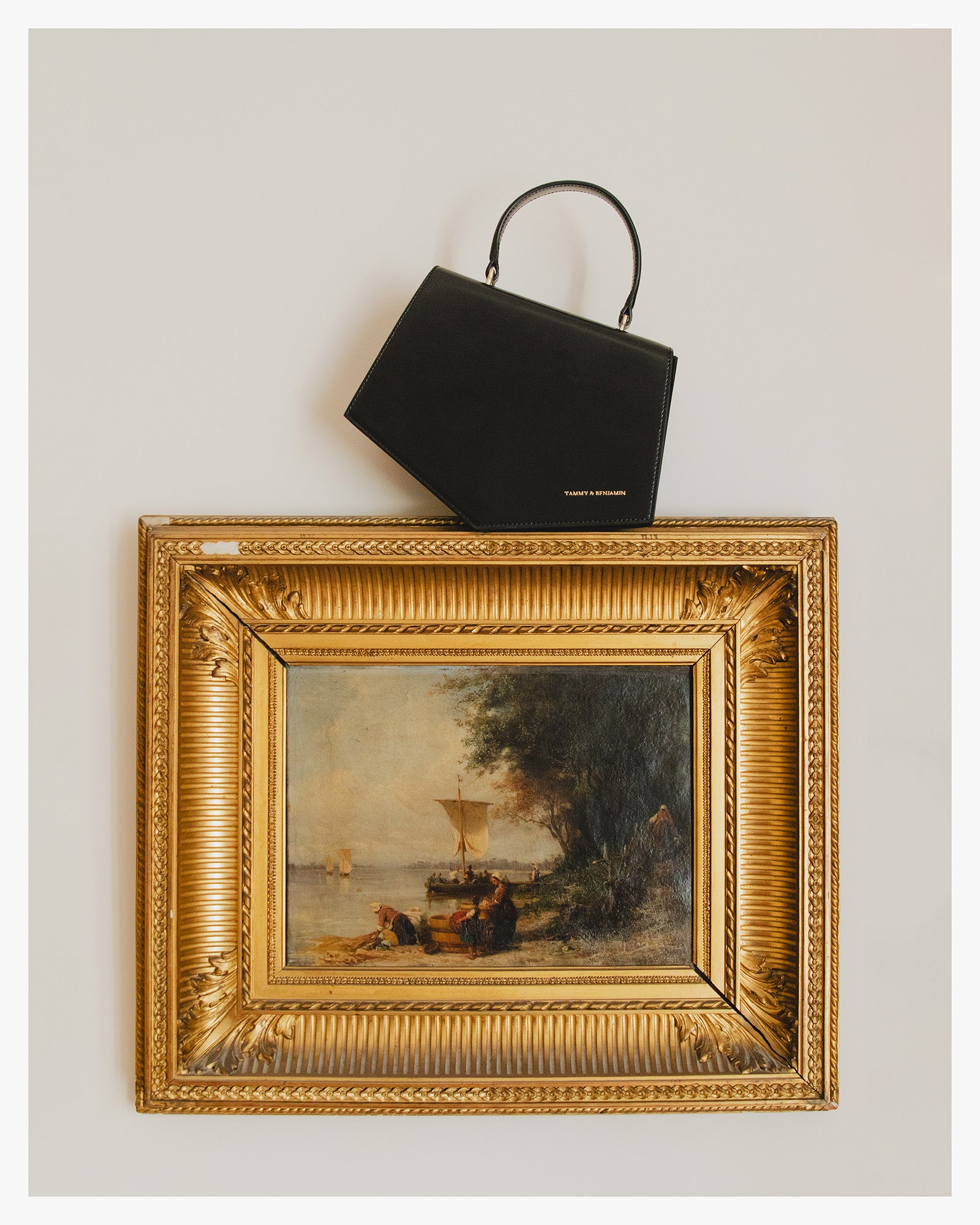 Sac PENTAGONE noir suspendu par son anse au cadre doré d'un tableau, posé en hauteur