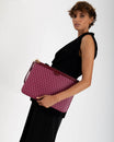 Pochette GM Monogram Bordeaux portée sous le bras, vue de côté, dragonne en cuir et zip apparents