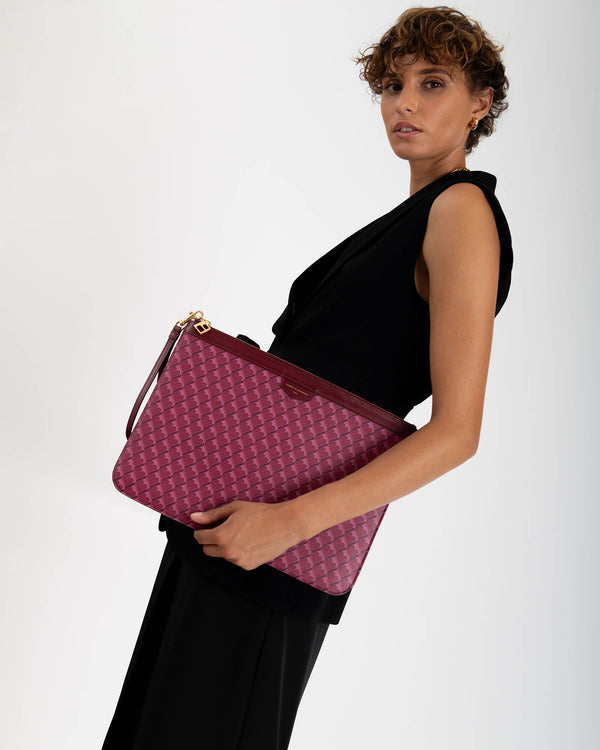 Pochette GM Monogram Bordeaux portée sous le bras, vue de côté, dragonne en cuir et zip apparents
