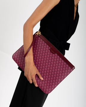 Pochette GM Monogram Bordeaux tenue à la main par la dragonne en cuir, motif monogram visible