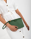 Pochette PM Monogram verte tenue à la main par sa dragonne, portée à la taille sur robe blanche