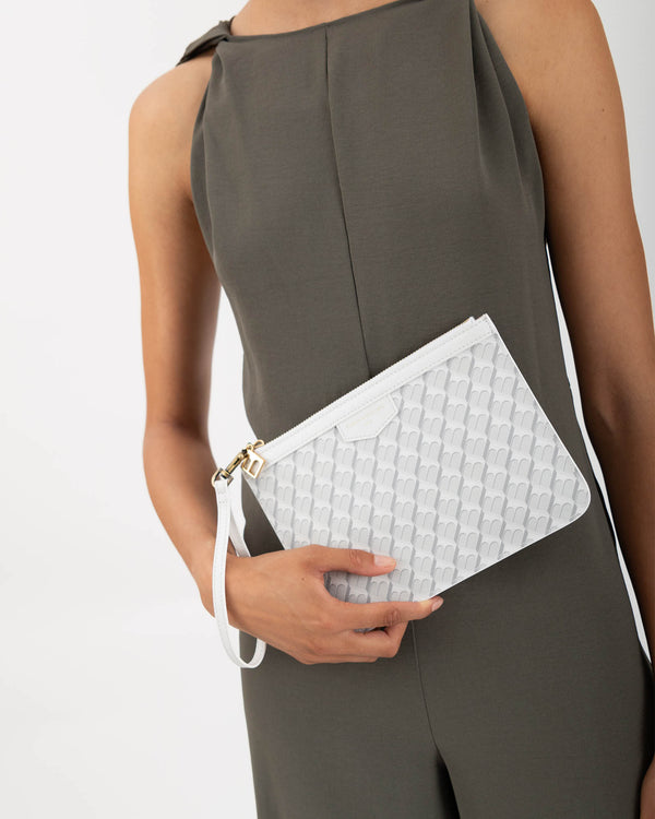 Pochette PM Monogram ivoire tenue à la main par sa dragonne, détail du motif monogram