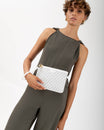 Pochette PM Monogram ivoire tenue à la main par sa dragonne, portée à la taille