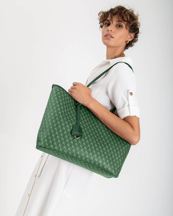 TOTE MONOGRAM vert, porté épaule, motif texturé et étiquette cuir visibles