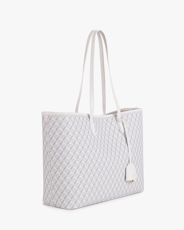 TOTE MONOGRAM blanc ivoire, vue de trois quarts posée, anses longues en cuir et motif monogramme