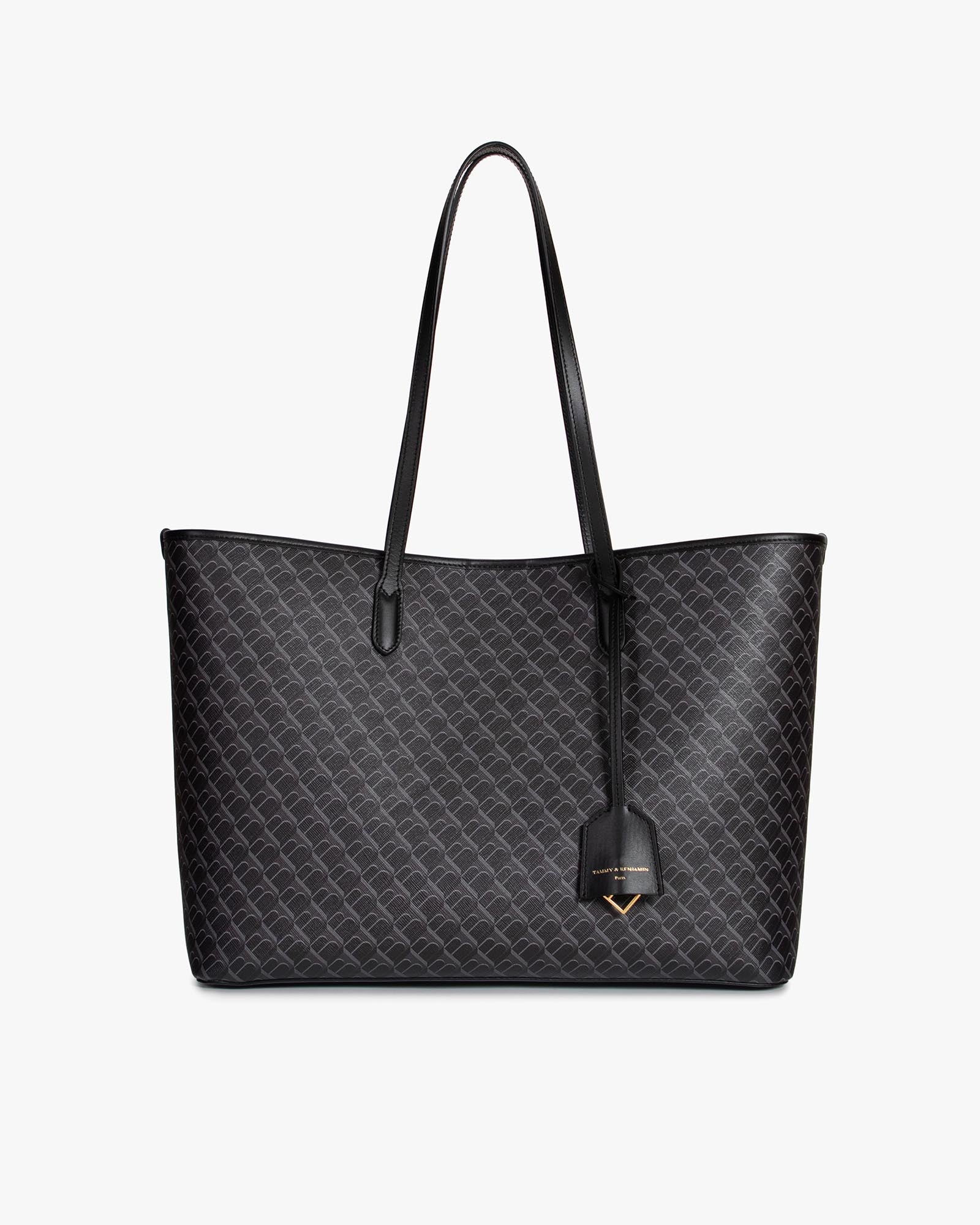 Sac TOTE MONOGRAM noir, vue de face, posé, anses longues en cuir et pampille logo