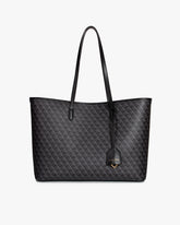 Sac TOTE MONOGRAM noir, vue de face, posé, anses longues en cuir et pampille logo