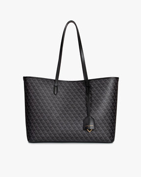 Sac TOTE MONOGRAM noir, vue de face, posé, anses longues en cuir et pampille logo