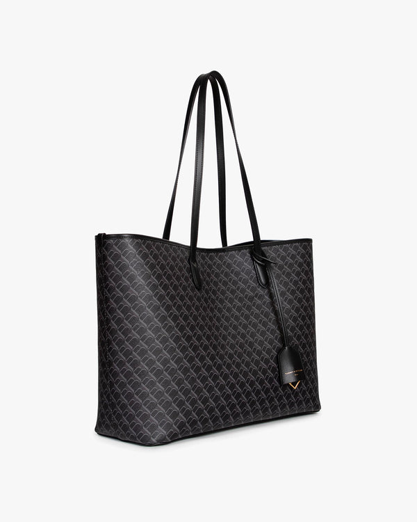 TOTE MONOGRAM noir, vue de trois quarts, anses longues en cuir, porté épaule, posé