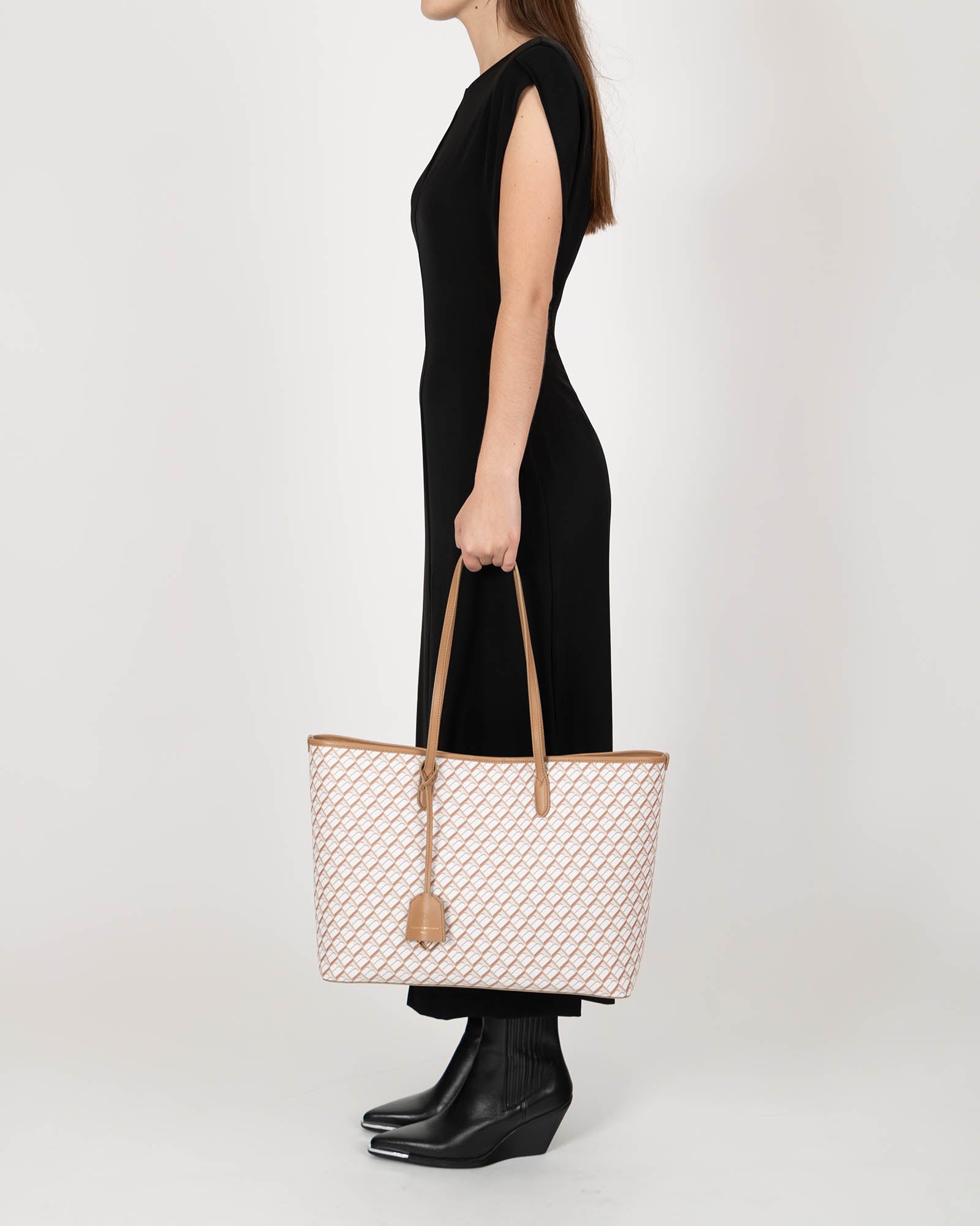 TOTE MONOGRAM Tan porté à la main, vue de profil, motif monogramme et anses en cuir