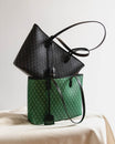 TOTE MONOGRAM PM vert, posé sur un tissu, anses noires, sac monogram noir glissé à l'intérieur