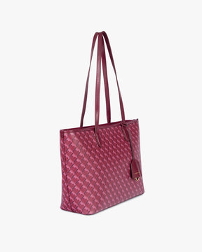 Sac TOTE MONOGRAM PM Bordeaux, vue de profil porté à l'épaule, anses plates et porte-étiquette apparents
