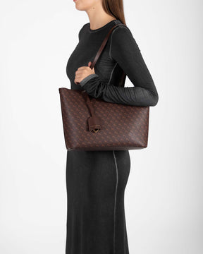 TOTE MONOGRAM PM Chocolate worn on the shoulder, side view on model, flat strap held in hand