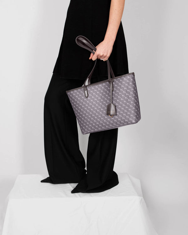 TOTE MONOGRAM PM gris, porté à la main, anses plates en cuir, vue de côté