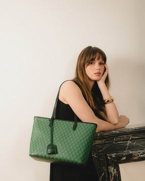 TOTE MONOGRAM PM vert porté à l'épaule, en toile enduite Marble Arch, par une femme assise