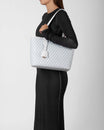 TOTE MONOGRAM PM blanc ivoire porté à l'épaule, vue de côté, motif monogramme en gros plan