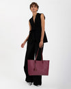 TOTE MONOGRAM Bordeaux porté à la main, vue de face sur mannequin en tenue noire