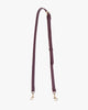 Bandoulière ajustable fine en cuir aubergine, posée à plat, boucle bijou et mousquetons laiton vieilli