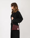 Sac TARA Mahogany porté en bandoulière, vue de profil sur un modèle en robe noire