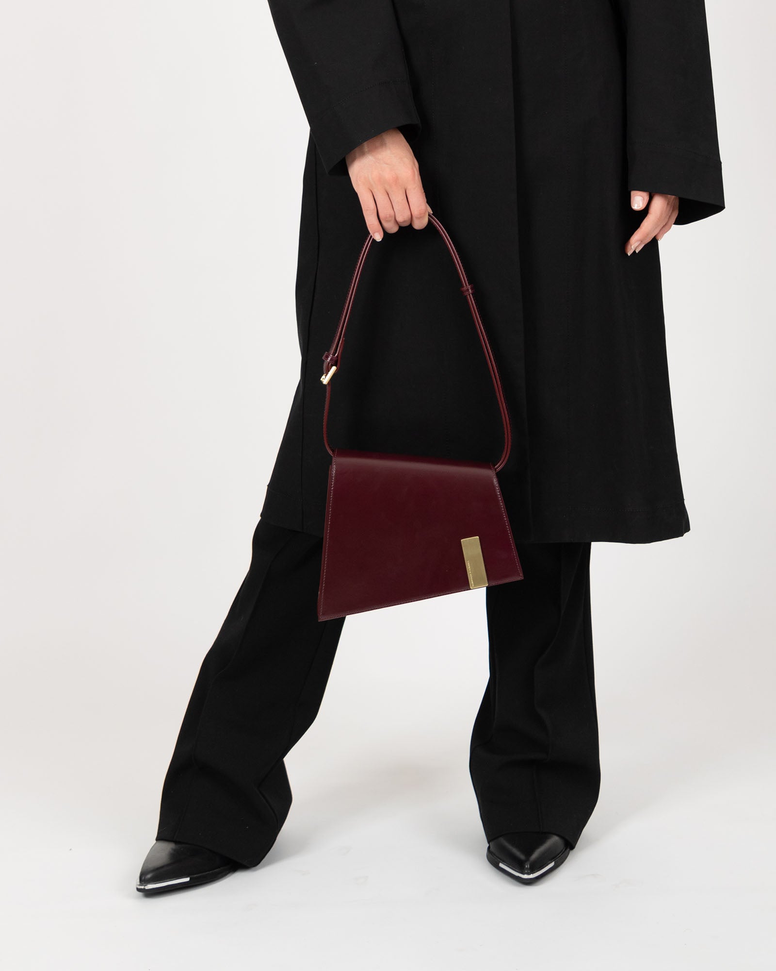 TARA Mahogany tenu à la main, bandoulière à l'épaule, vue de face du sac porté