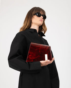Pochette TARA Marbre tenue à la main contre la poitrine, portée par une mannequin de profil