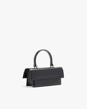 THEA MINI bag in black naplak, rear three-quarter view, standing, showing flap and handle