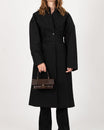 Sac THEA MINI brun embossé lézard, porté à la main par un mannequin en manteau noir