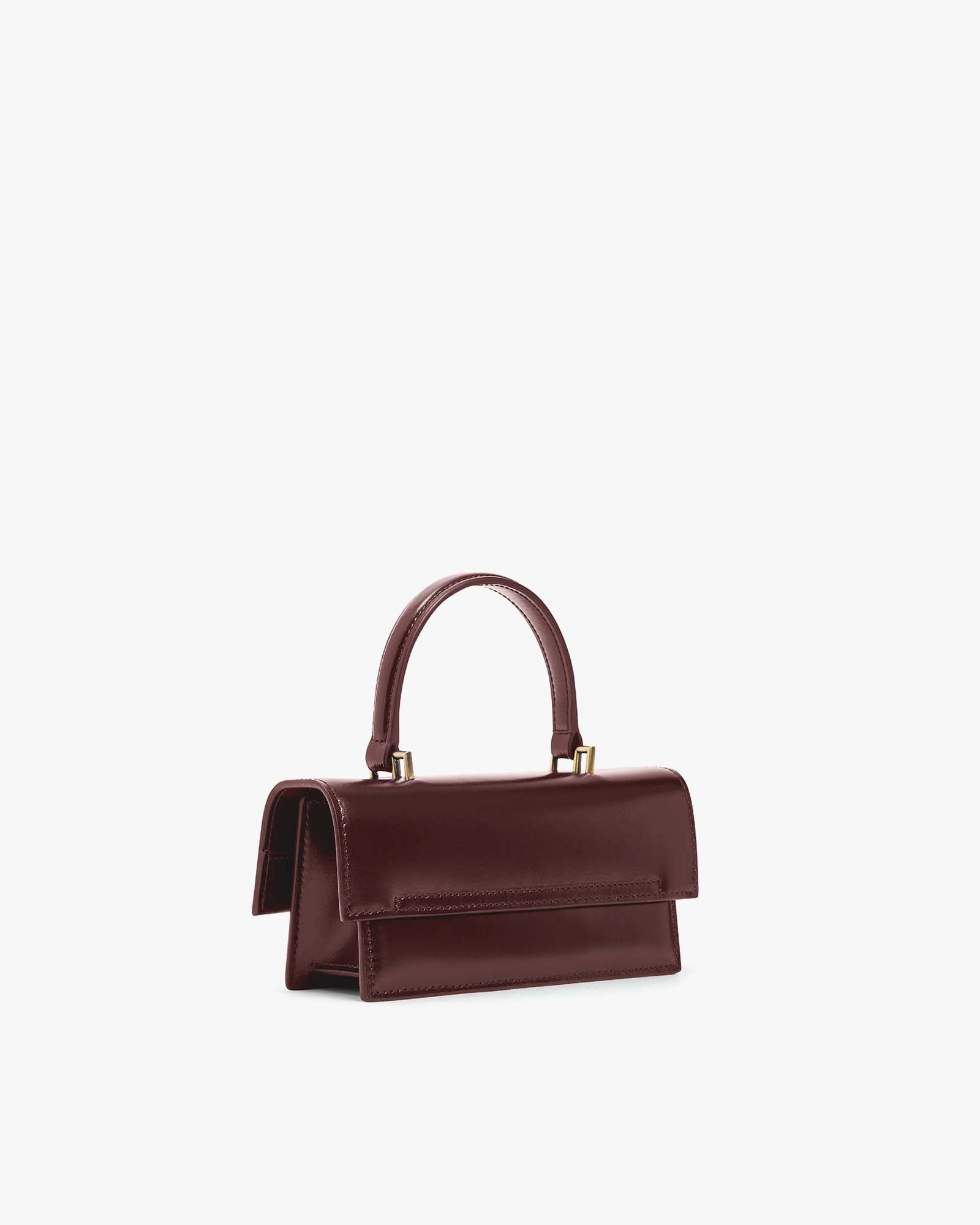 THEA MINI bag in Mahogany, side view, placed down, flap closed with top handle raised