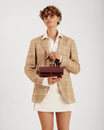 THEA MINI bag in Mahogany held by a woman in a blazer, front view