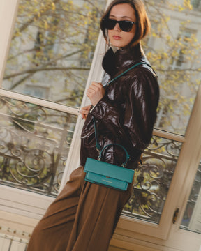 THEA MINI turquoise bag worn crossbody, side view, flap and handle detail