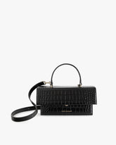 Sac THEA Noir - Embossé Crocodile de face, poignée rigide et bandoulière détachée, posé