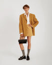 Sac THEA noir porté à la main par anse rigide, tenue oversize jaune moutarde