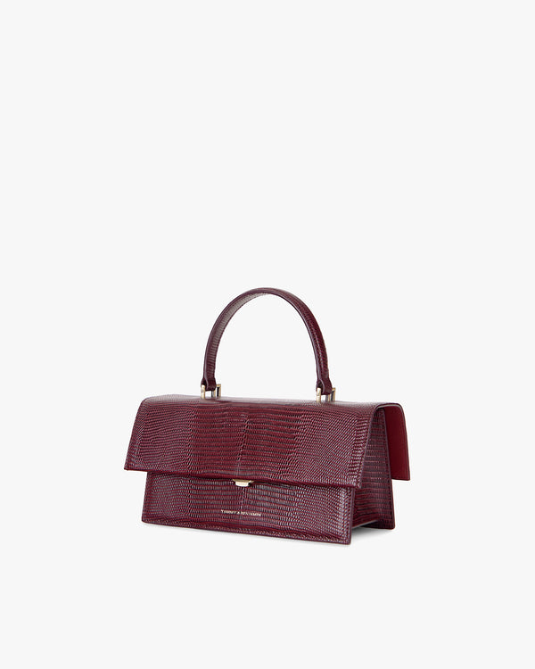 Sac THEA Bordeaux embossé lézard, vue de trois-quarts, rabat fermé, poignée rigide relevée