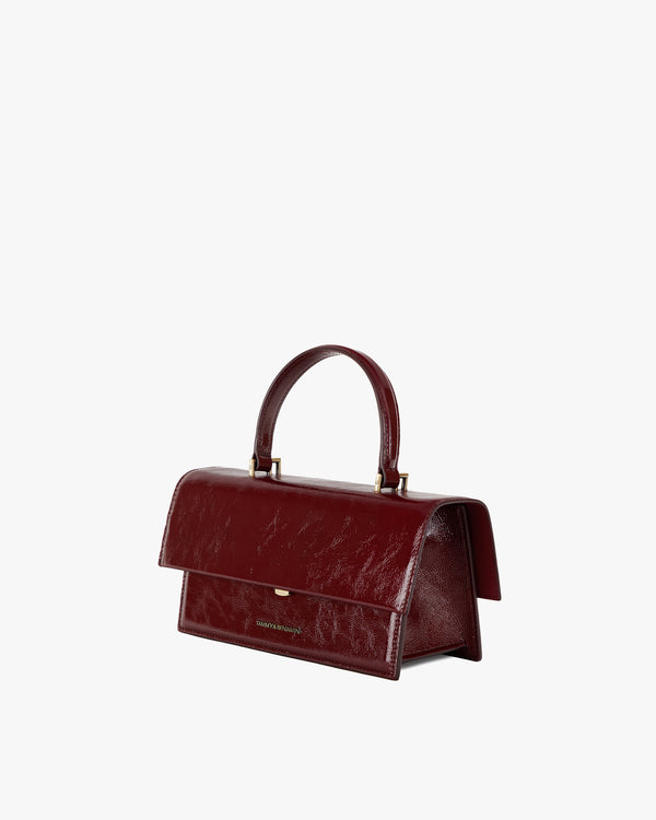 Sac THEA Bordeaux naplak, vue de trois quarts, rabat oversize fermé, posé sur fond blanc