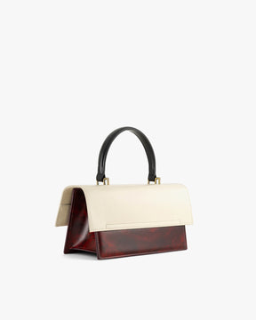 Sac THEA Colourblock art déco de profil, rabat surdimensionné, anse noire, posé