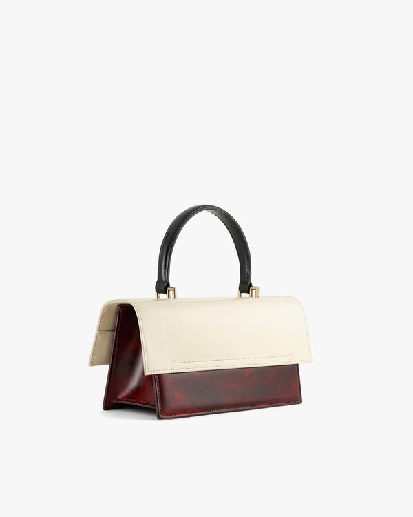 Sac THEA Colourblock art déco de profil, rabat surdimensionné, anse noire, posé