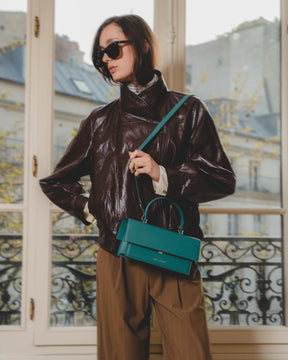 Sac THEA turquoise porté en bandoulière, poignée rigide, vue de face sur un mannequin
